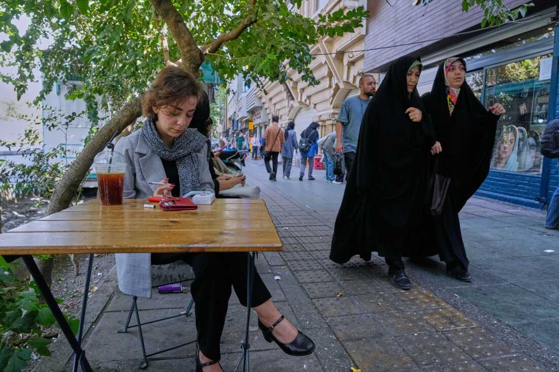 A woman sits in the al fresco dining area of a cafe at the Enqelab-e-Eslami (Islamic Revolution) street, in Tehran, Iran, Saturday, Sept. 27, 2025.