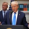 President Trump stands at the microphone at the White House in front of a shelf of books.