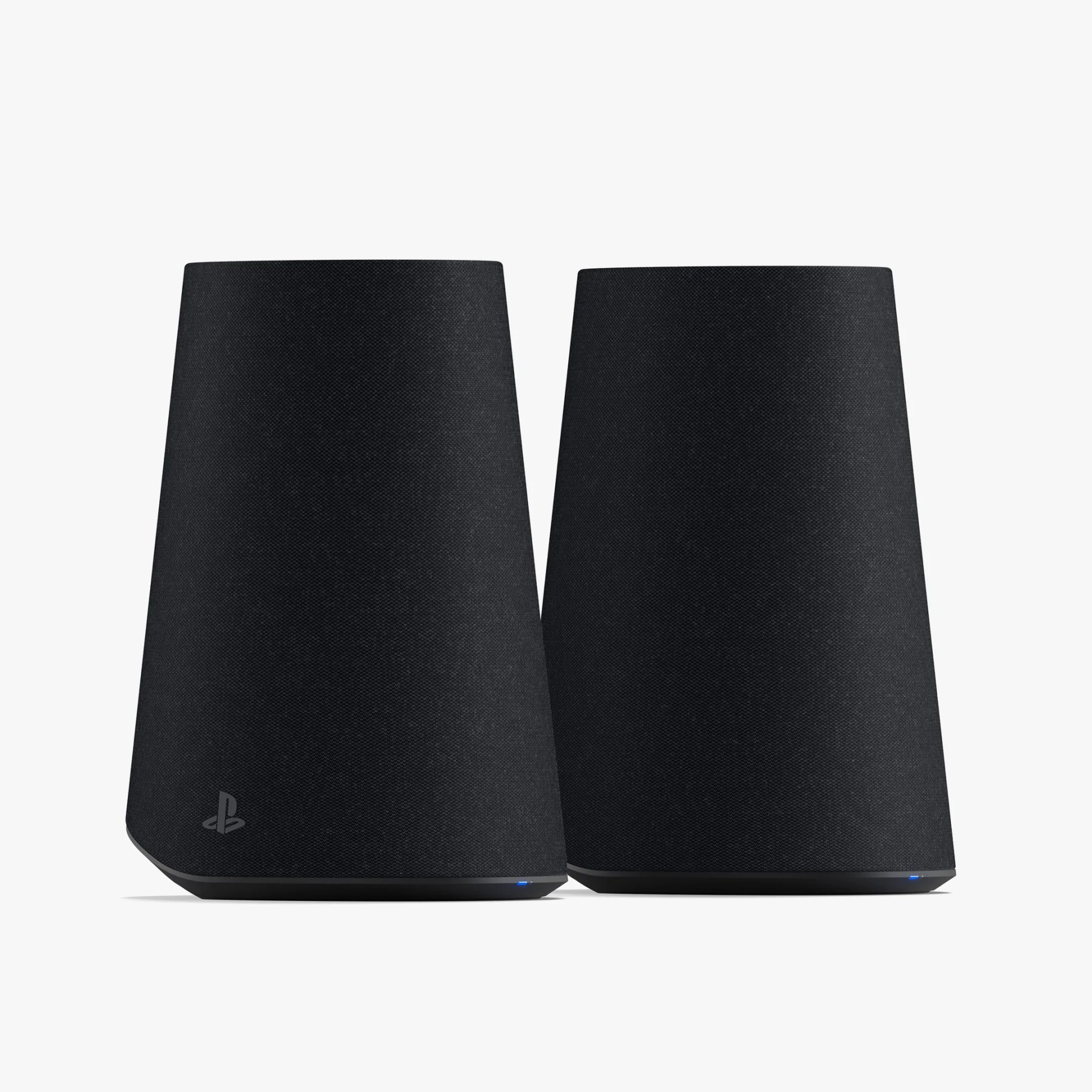 Two black, trapezoidal-shaped wireless speakers with fabric covers, each featuring a small blue LED light near the base. One speaker has a subtle PlayStation logo near the bottom.