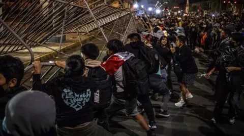 John Reyes Mejia/EPA/Shutterstock Young students push over metal barriers erected by the security forces around the building housing Peru's Congress. 
