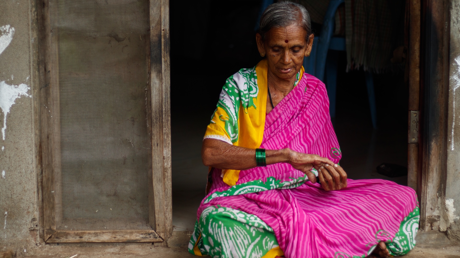 A photo of an Indian woman in traditional attire looking at psoriasis on her hand and arm