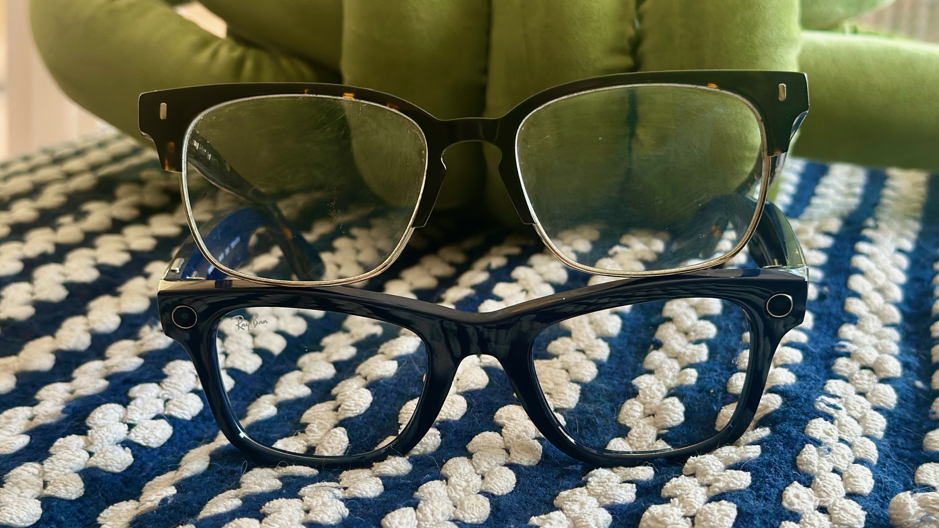 Photo of normal Warby Parker glasses sitting atop Ray-Ban Meta (Gen 2) Wayfarer glasses on a blue-and-white patterned blanket.